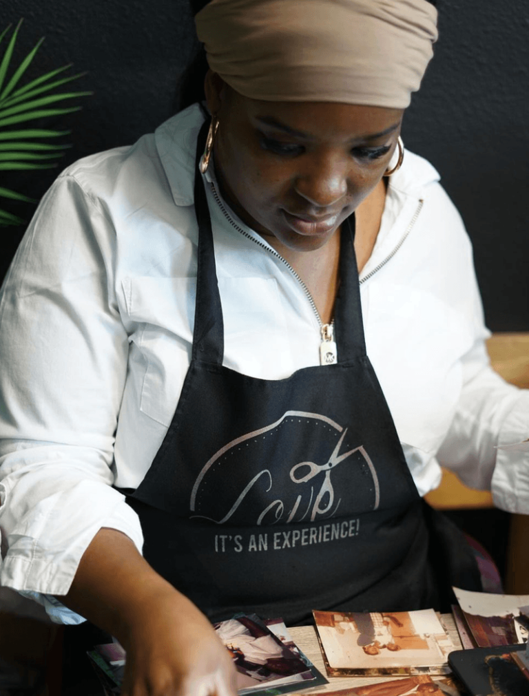 Hadassa, founder of Love 518 Method, wearing a branded apron while reviewing her portfolio